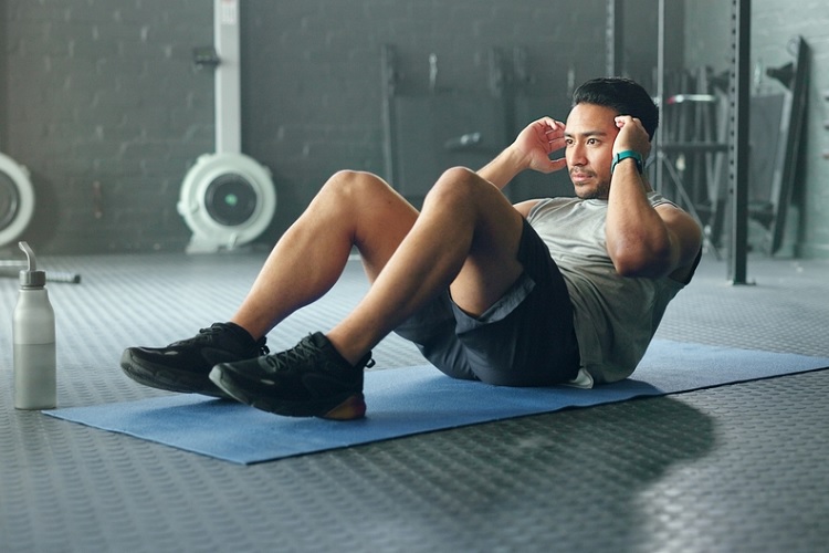 Exercise Addiction concept featuring a man performing intense abdominal exercises on a gym mat, representing compulsive exercise and excessive workout habits.