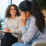 Counselor listening to a stressed woman during a session, reflecting Accreditation in Rehab standards.