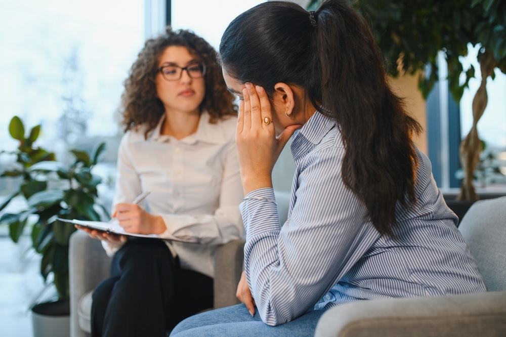 Counselor listening to a stressed woman during a session, reflecting Accreditation in Rehab standards.
