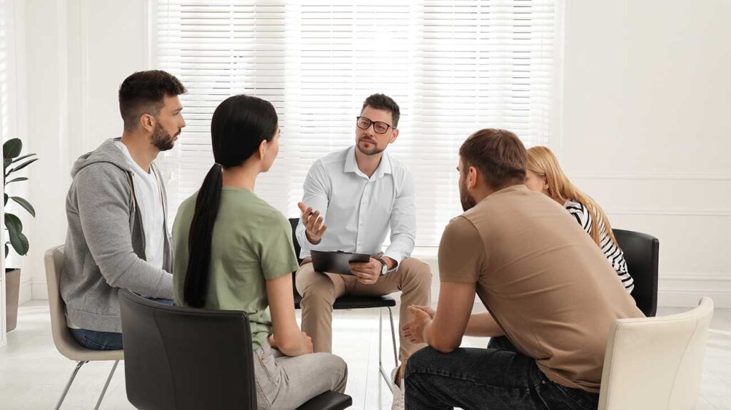 Therapist leading a group therapy session with patients, highlighting Accreditation in Rehab.