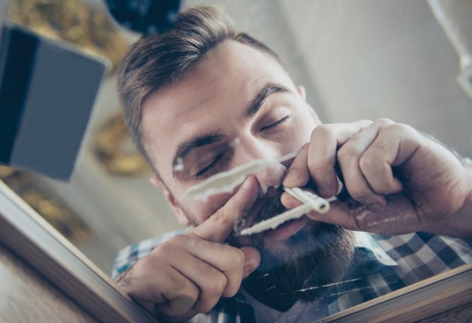 Low-angle shot of a man snorting white powder through a rolled bill, illustrating habits that lead to severe Cocaine Nasal Damage