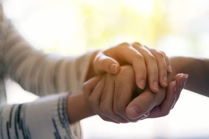 Gentle close-up of hands holding tightly in comfort, showing constructive empathy to balance enabling vs helping addiction.