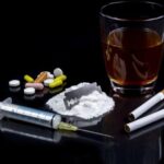 Alcohol, pills and a syringe show substance risks, emphasizing the need for Kindness in Recovery to overcome addiction.