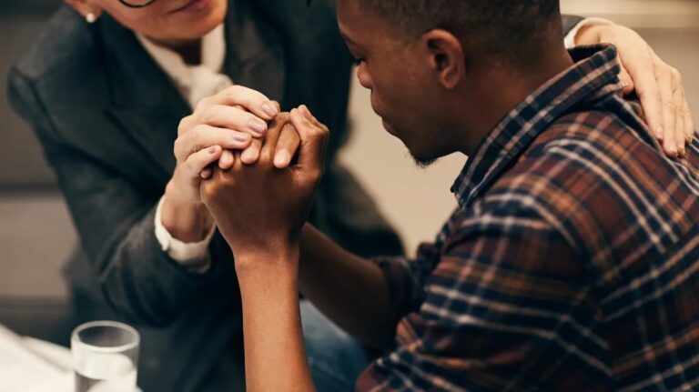 Compassionate counselor holding hands with a patient at an addiction treatment center Fort Wayne.