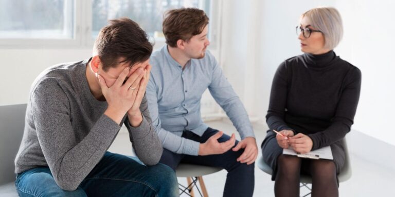 Therapist counseling a distressed man in a group session at a luxury addiction treatment center.