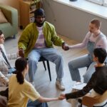 A diverse group sitting in a circle holding hands during a therapy session at a private ranch rehab facility to build mutual support and healing.