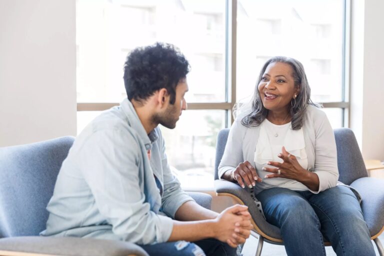 Friendly senior counselor speaking with a young adult patient to verify insurance for rehab coverage.